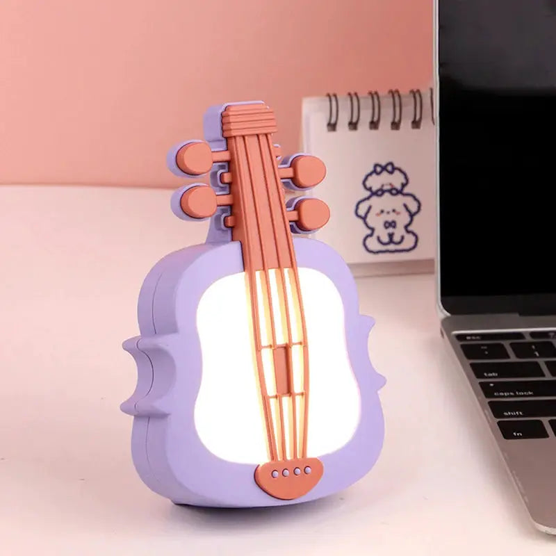 Guitar-shaped LED night light with lavender body and orange strings for desk use