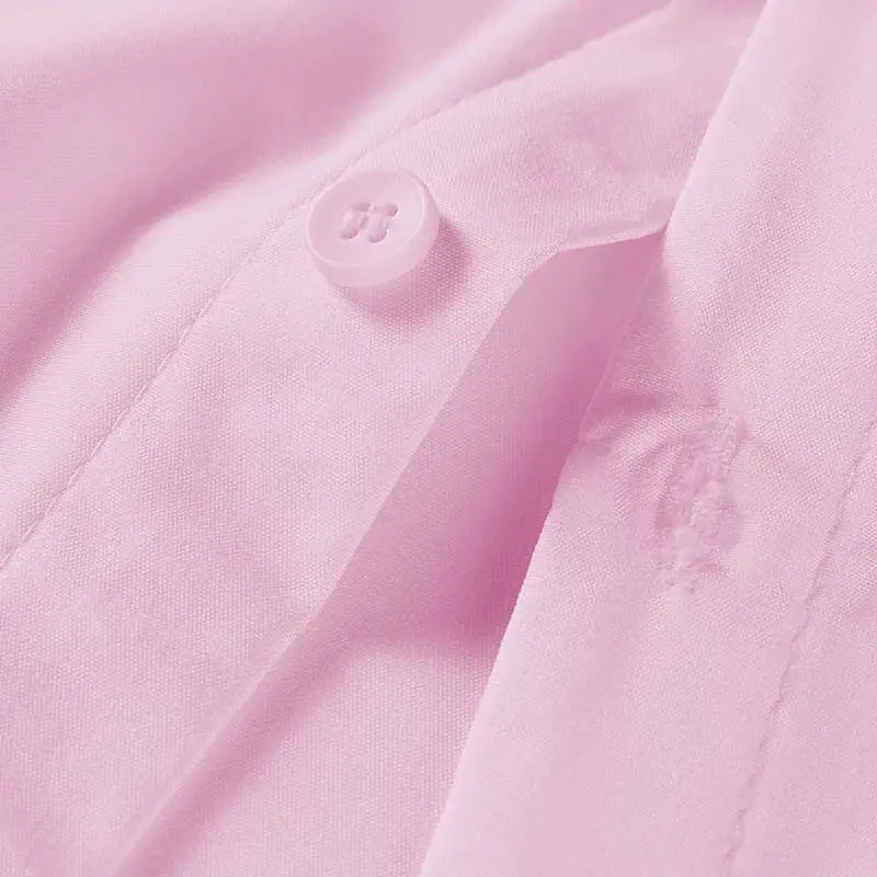 Men's pink solid short-sleeve shirt close-up showing button and fabric texture