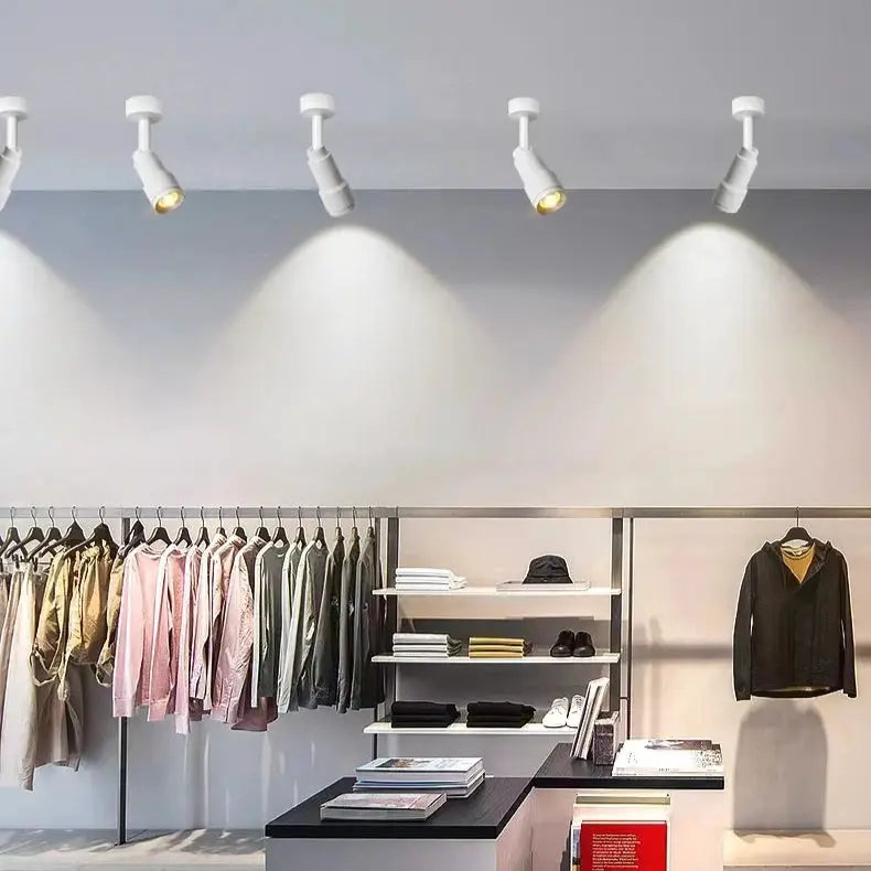 White adjustable LED ceiling spotlights, a 4-pack on track lighting over a clothing store display.