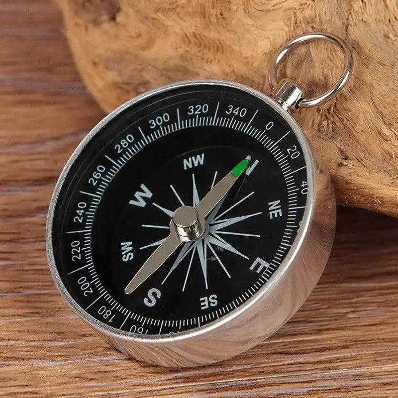 Mini aluminum alloy compass keychain pendant by Simples Market; black dial, silver case, green-tipped needle.