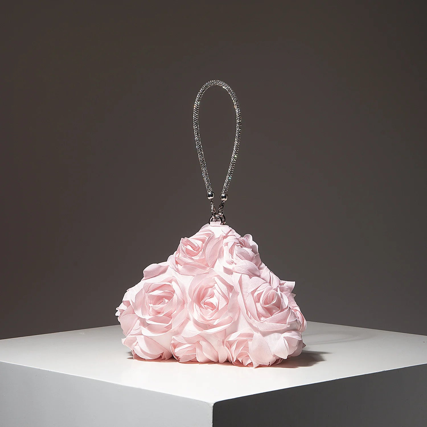 Mini purse with a glittering rhinestone strap on a pink fabric rose bouquet display