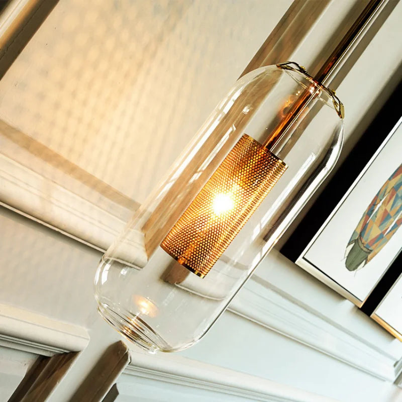 Modern glass wall sconce with a clear cylindrical shade and warm copper-mesh LED inner tube