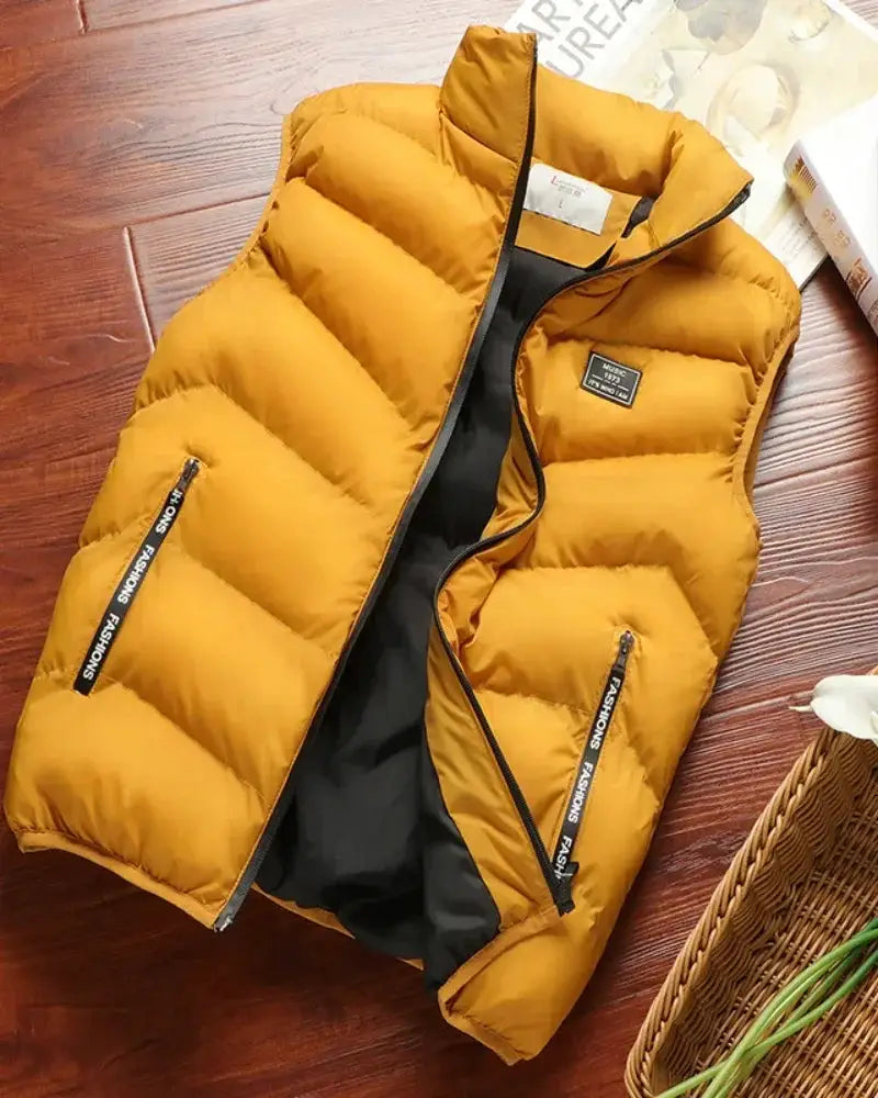 Men's mustard yellow puffer sleeveless vest with black lining, solid color outerwear and branded zipper pockets.