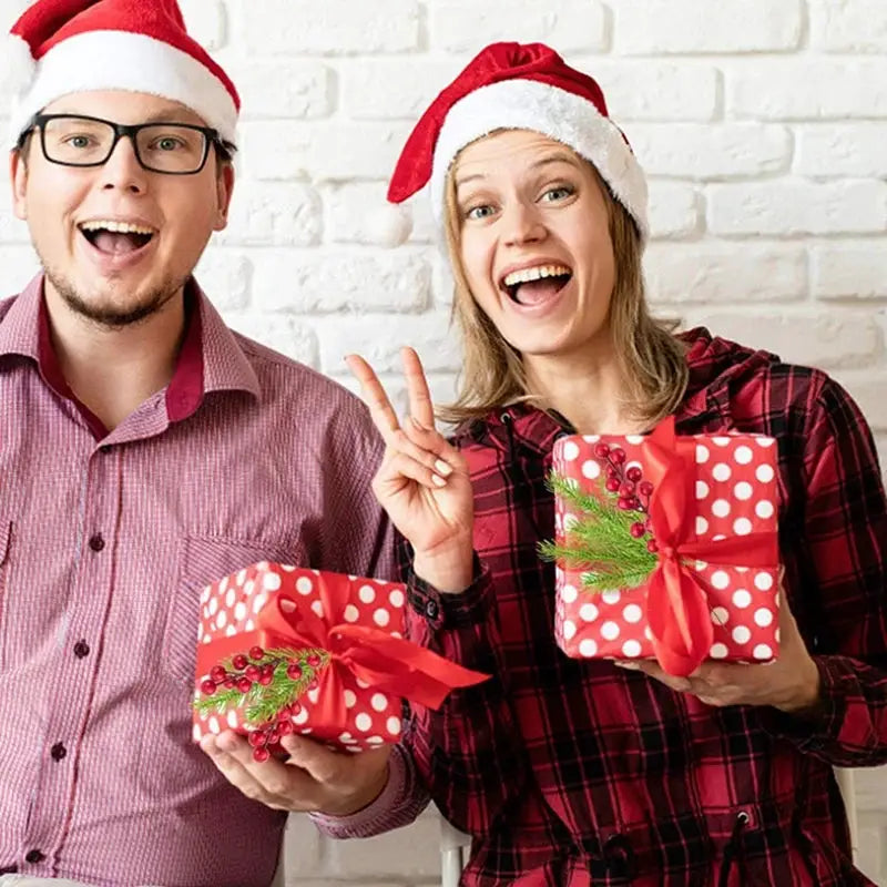 Gift boxes with red polka dots and holly sprigs, held by two people in Santa hats
