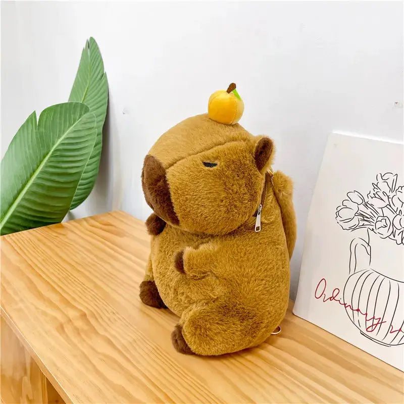 Cute plush capybara backpack in brown with zipper, orange fruit on head, adorable kawaii crossbody bag