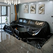Waterproof black sofa cover in PVC vinyl over an L-shaped living room couch; round coffee table also wrapped