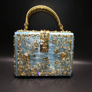 Evening bag with blue body, crystal accents and ornate gold filigree on a gold handle.