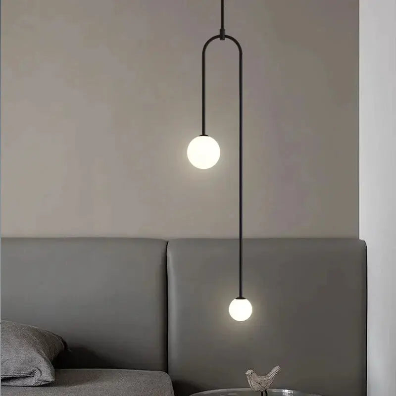 Two-globe glass pendant light with a vertical black hanging rod and warm LED illumination