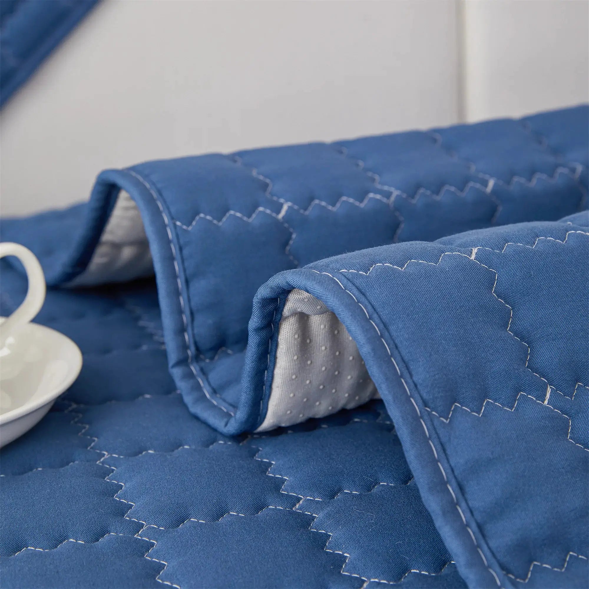 Sofa slipcover in blue quilted fabric with anti-slip backing