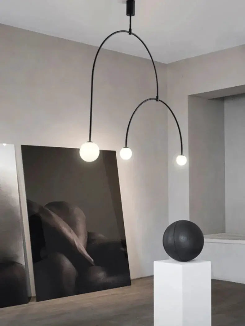 Nordic minimalist chandelier with two curved black metal arms and three white globe bulbs