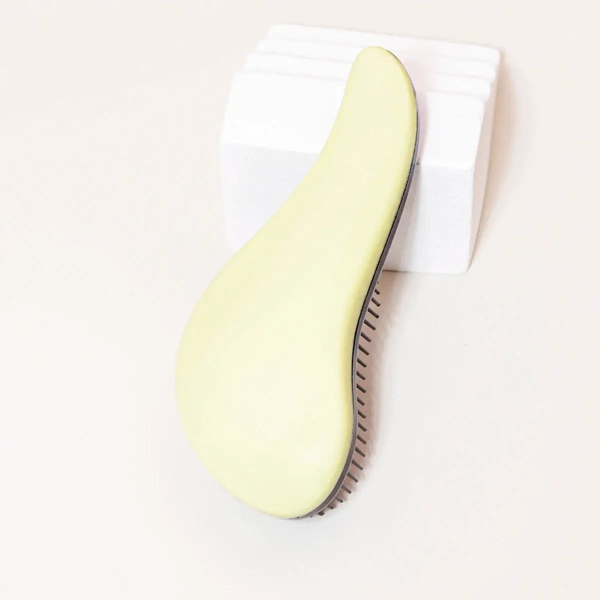 Antistatic massage brush with pale yellow curved handle and black bristles, salon hairdressing tool