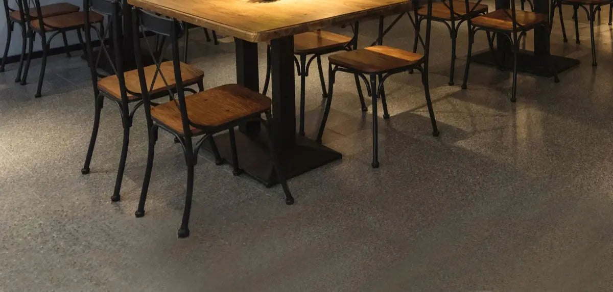 Cafe dining area with wooden tables and black metal chairs on a polished concrete floor