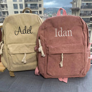 Two personalized corduroy kids backpacks in beige and pink with embroidered names Adele and Idan