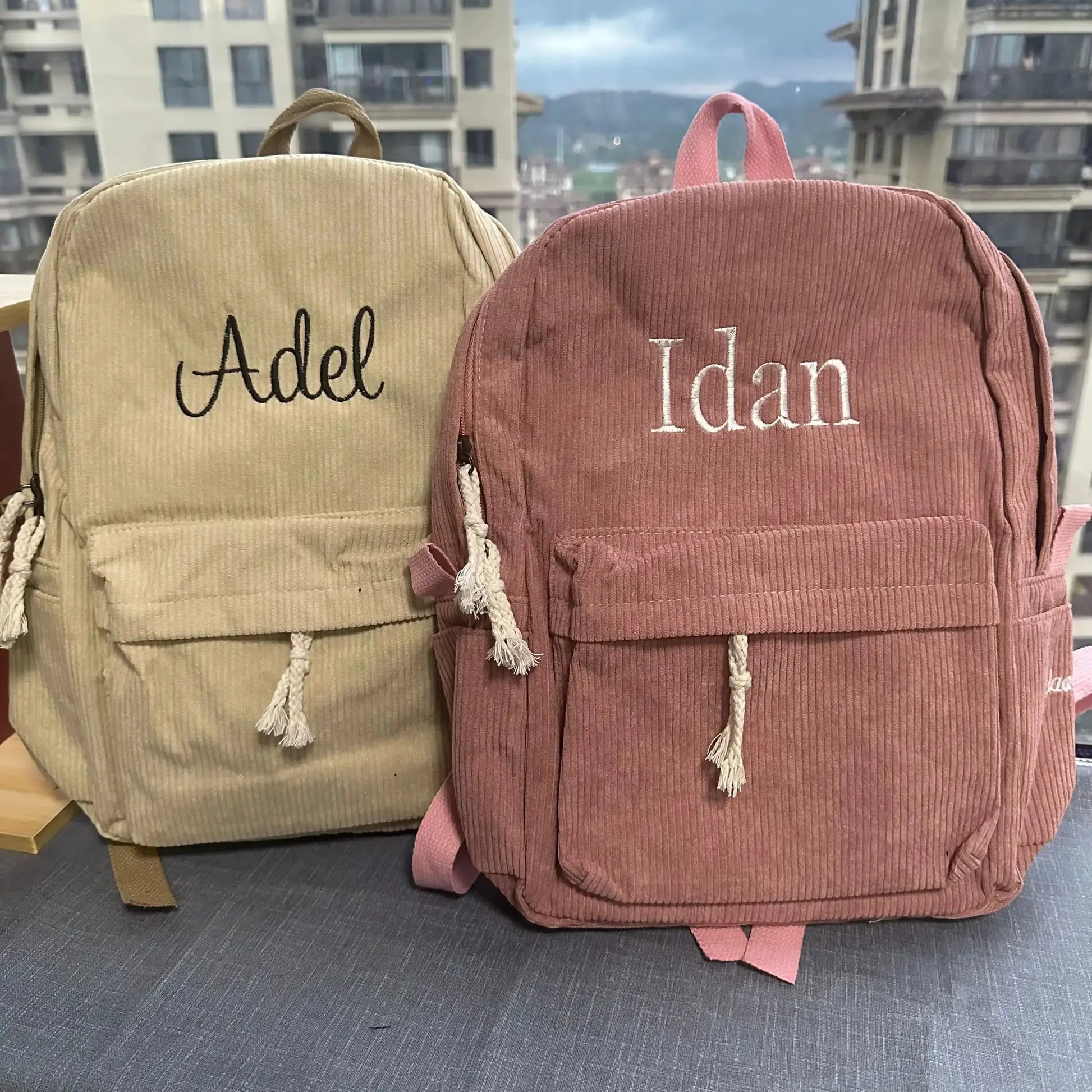 Two personalized corduroy kids backpacks in beige and pink with embroidered names Adele and Idan