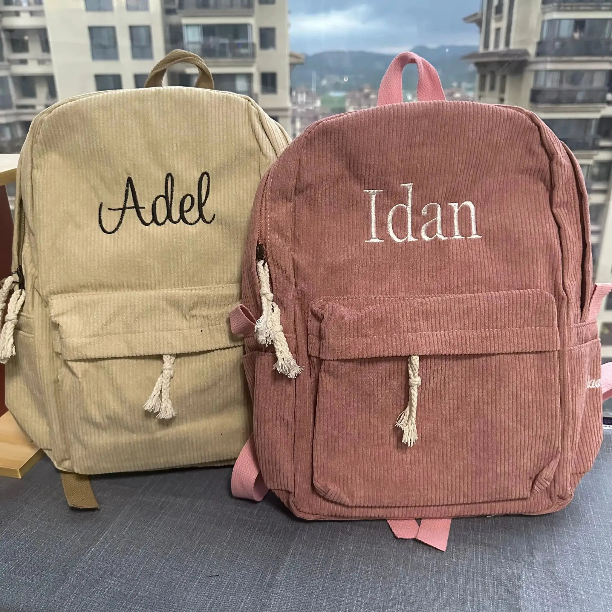 Two personalized corduroy kids backpacks in beige and pink with embroidered names Adele and Idan