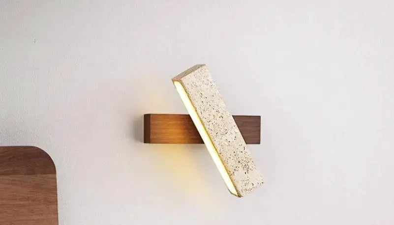 Natural stone wall lamp sconce with wooden backplate and diagonal beige stone block emitting warm light