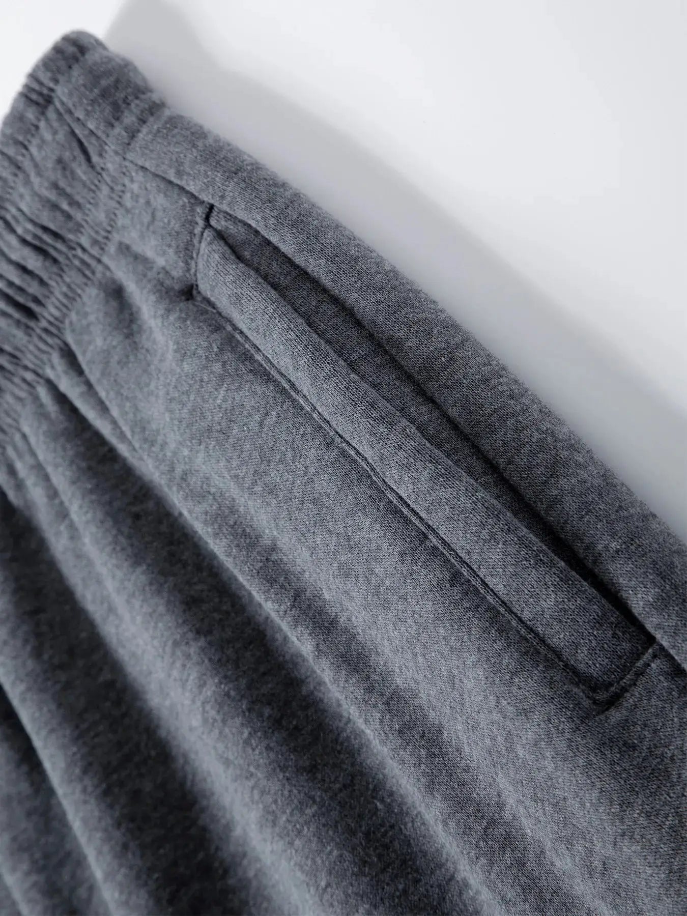 Men's gray jogger pants; fabric close-up shows soft knit texture