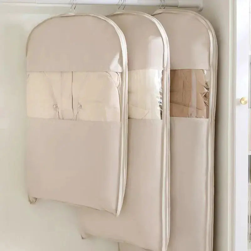 Wardrobe compression bags hanging in closet; three beige fabric organizers for space-saving storage.