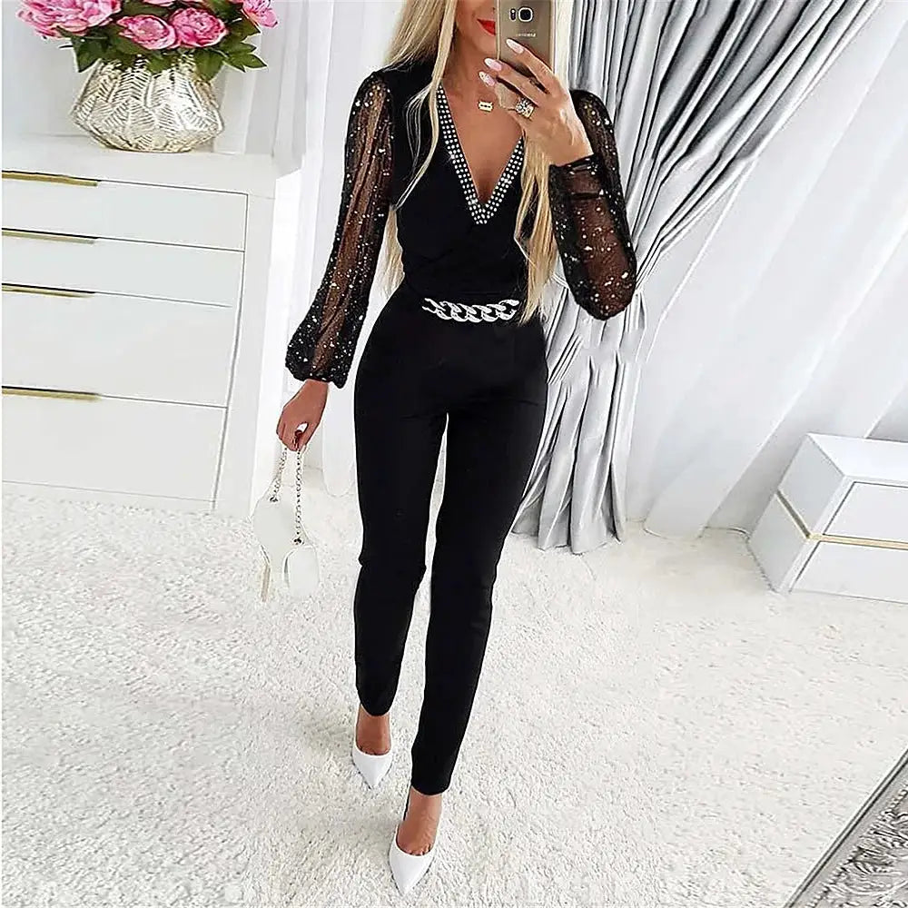 Jumpsuit Simples Market: black V-neck one-piece with sheer dotted sleeves, chain belt, white heels