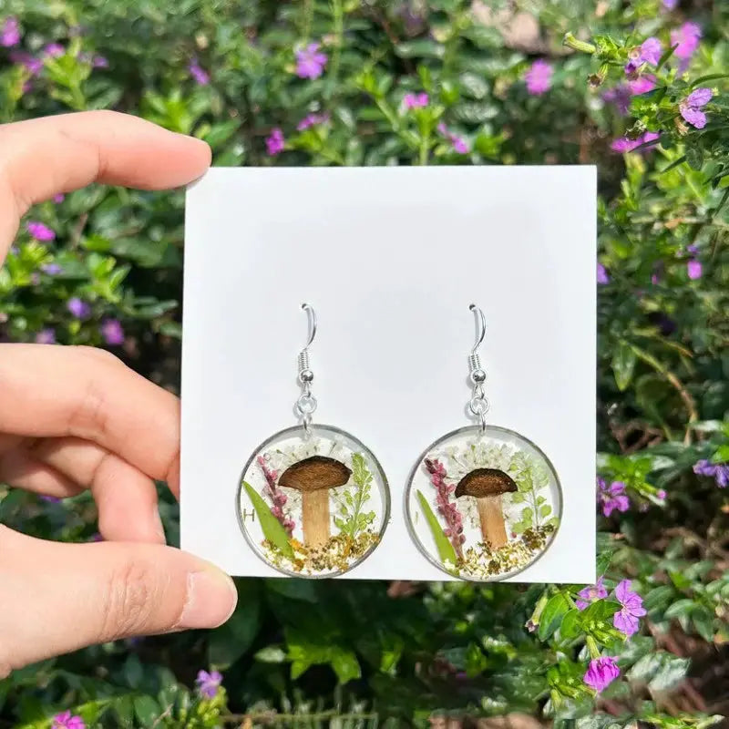 Pair of circular epoxy resin earrings with pressed flowers and natural botanicals