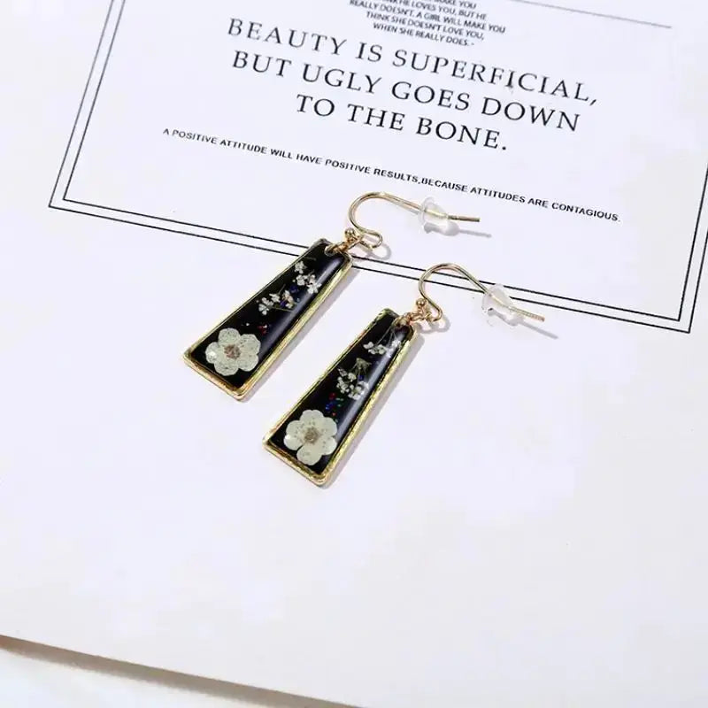 Pressed flower earrings, black epoxy rectangular shapes with gold frames and white blossoms, pair