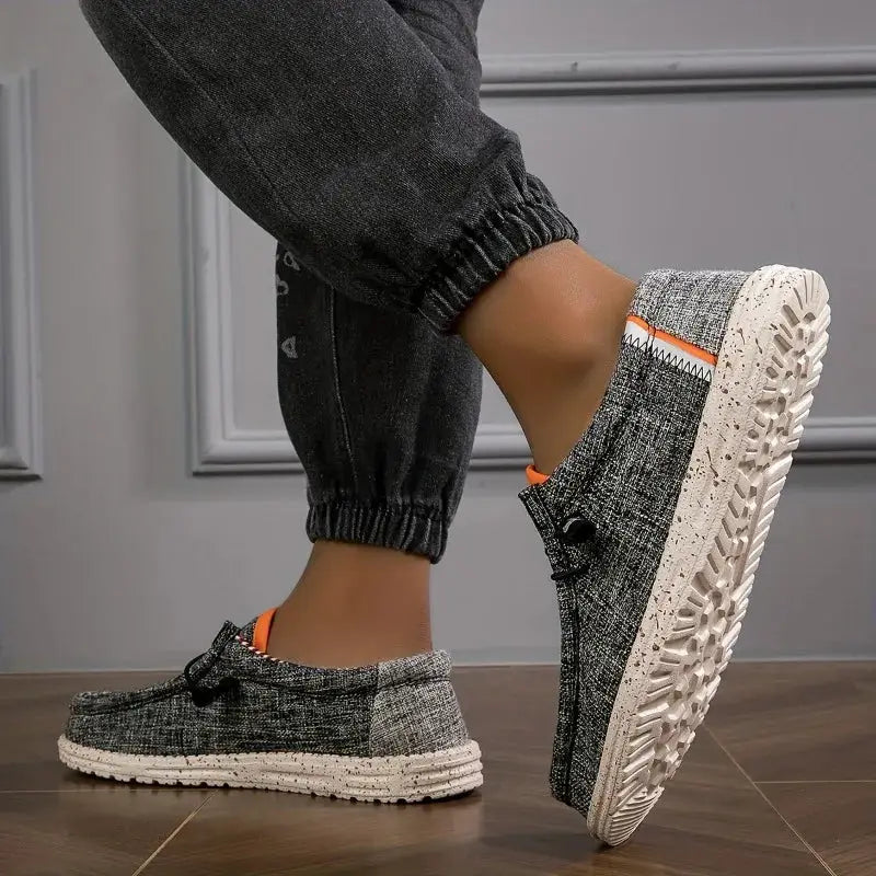 Men's canvas loafers in gray textured fabric with orange trim and speckled white sole.
