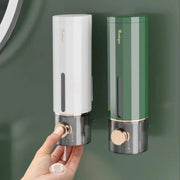 Manual wall-mounted bathroom soap dispensers by Simples Market; white and green finishes with gold trim, two shown