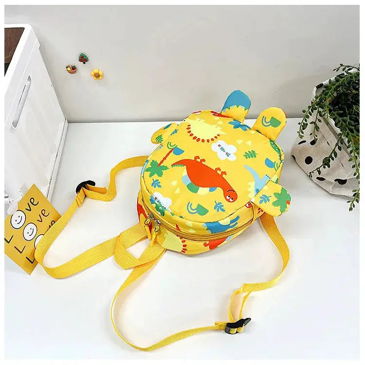 Yellow round kids backpack with cartoon dinosaur print and adjustable straps.