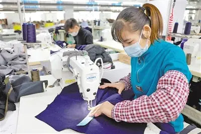 Ladies bodysuit being sewn on purple fabric at an industrial sewing machine in a factory
