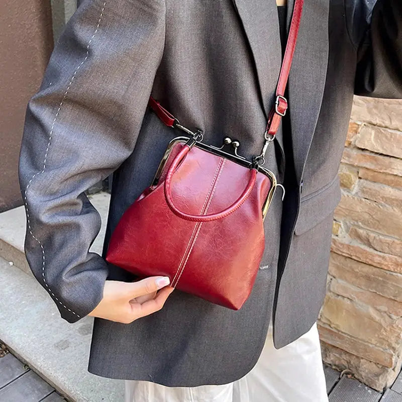 Vintage-style burgundy PU leather handbag with metal clasp frame and red crossbody strap