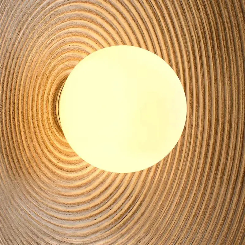 Retro Japanese Resin Wall Lamp by Simples Market, warm white globe on textured wall with concentric rings.