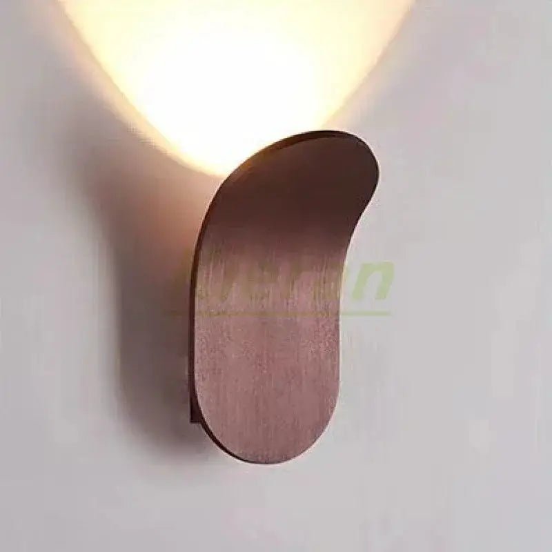 Nordic modern skateboard LED wall lamp in wood finish, casting warm upward light on wall