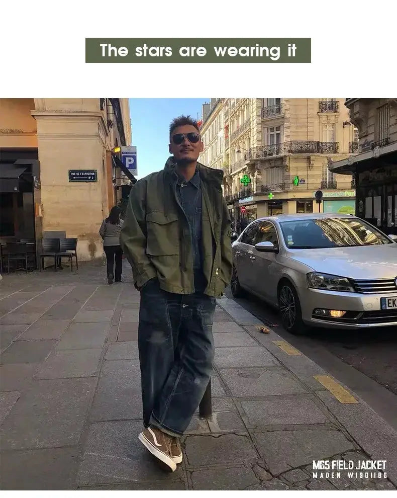 Maden M65 field jacket in olive green, military-style windbreaker with front pockets, worn by man on a city street.