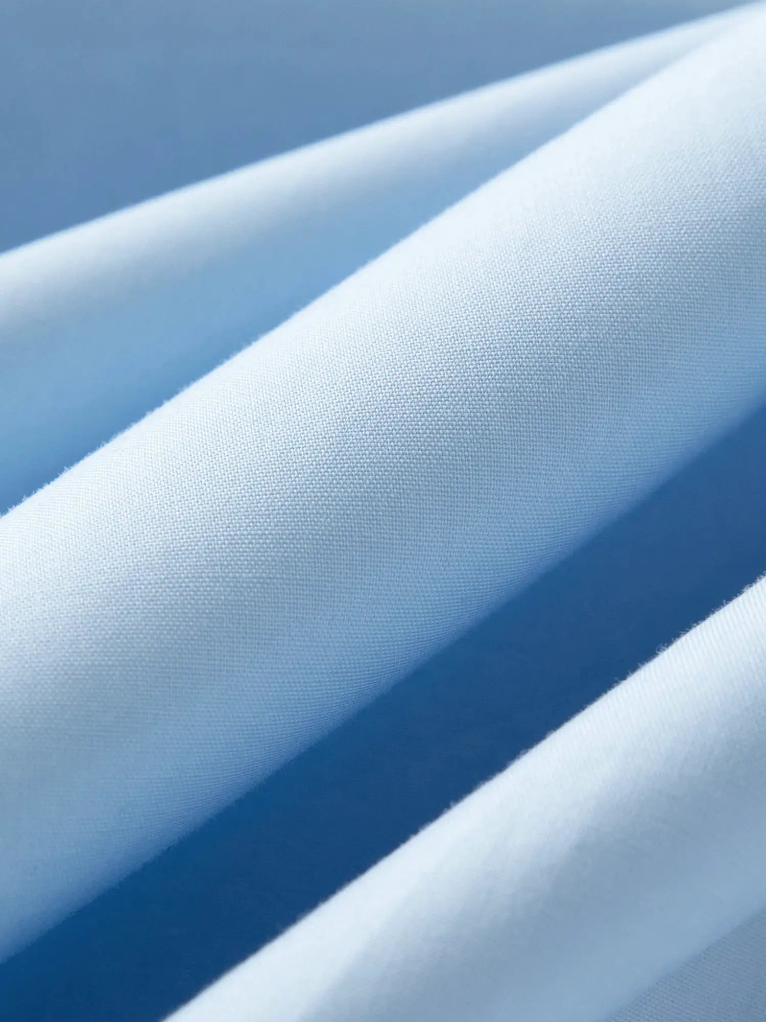 Light blue cotton shirt fabric close-up showing fine weave and smooth texture.