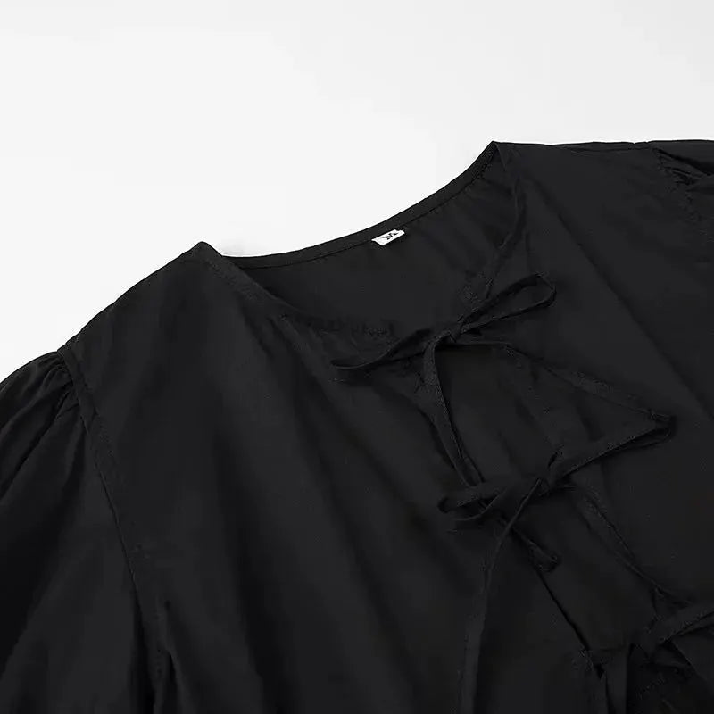 Simples Market black puff-sleeve blouse with tie-neck and ruffle front.