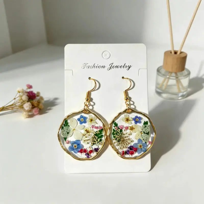 Pressed flower epoxy resin earrings with gold-tone circular frames and colorful floral inlays, pair