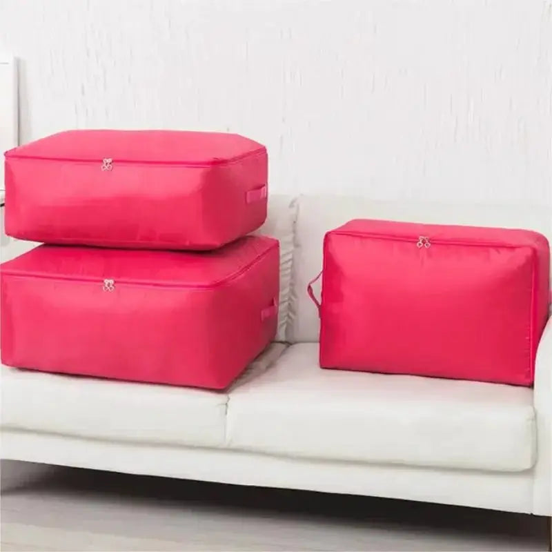 Zipper clothes organizer bags in pink; set of three for bedding storage on a white sofa