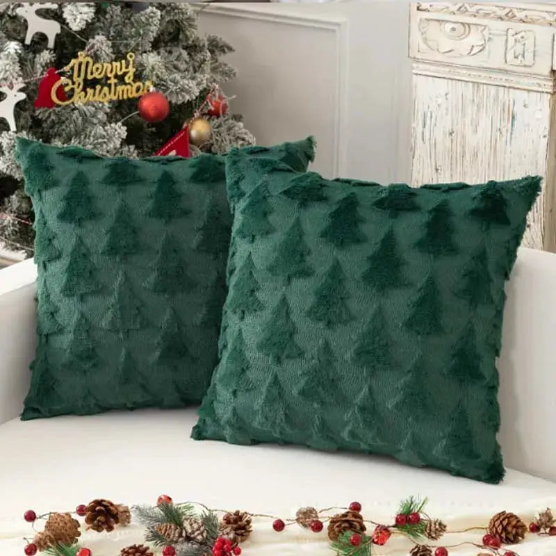 Two dark green textured decorative pillow covers on a white couch with a Christmas tree in the background.