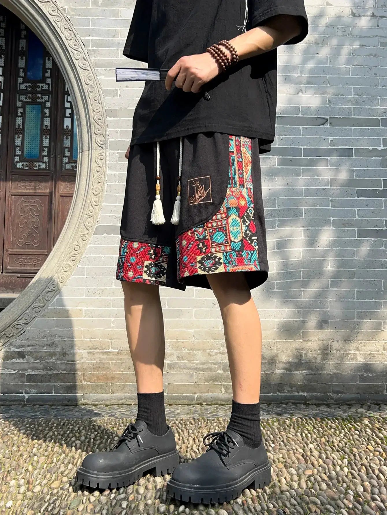 Simples Market men's ethnic embroidery shorts with pockets; black with patchwork side panels and tassel drawstrings