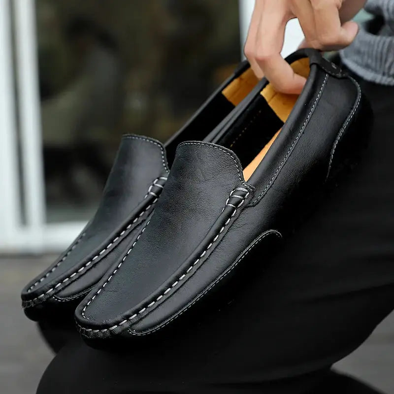 Pair of men's black genuine leather loafers by Simples Market, slip-on casual driving moccasins with white stitching