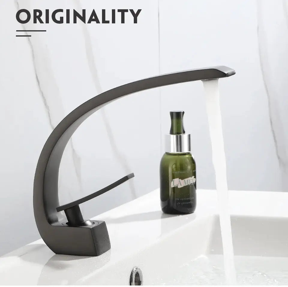 Basin faucet in black/gold finish with curved arched spout and single-handle mixer for hot and cold water, waterfall flow.