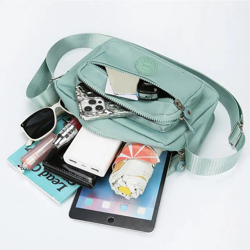 Mint green cross-body bag with multiple zip pockets and adjustable strap, ideal for work and study.