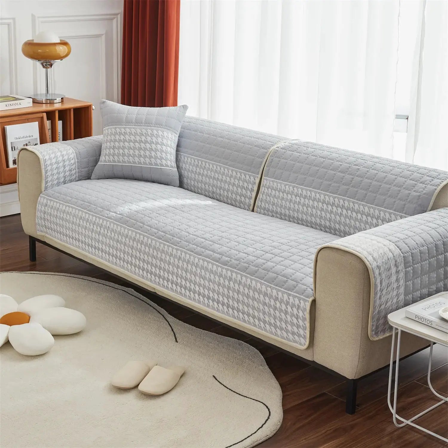 Houndstooth quilted sofa slipcover in light gray with anti-slip backing on a beige sofa.