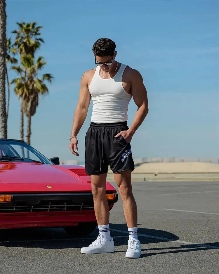 Trend men's black mesh quick-dry beach shorts, jogger style worn by man in white tank top and sneakers