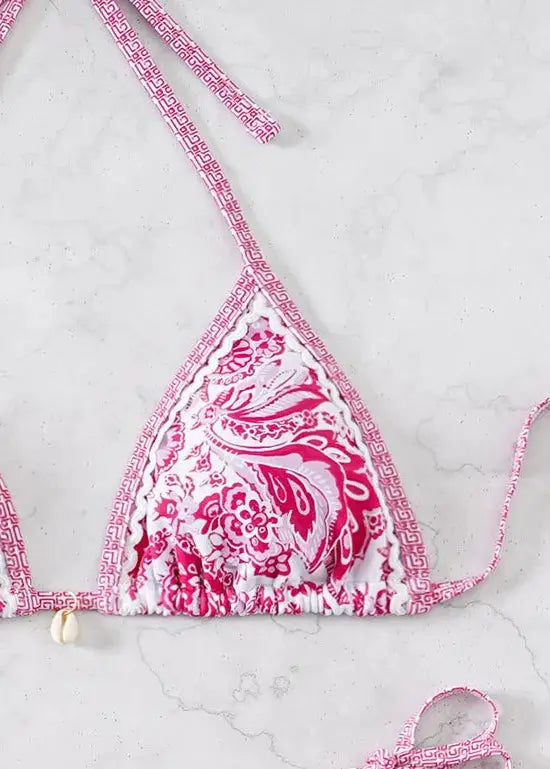 Triangle bikini top in pink floral print with white background and pink geometric trim; adjustable string ties