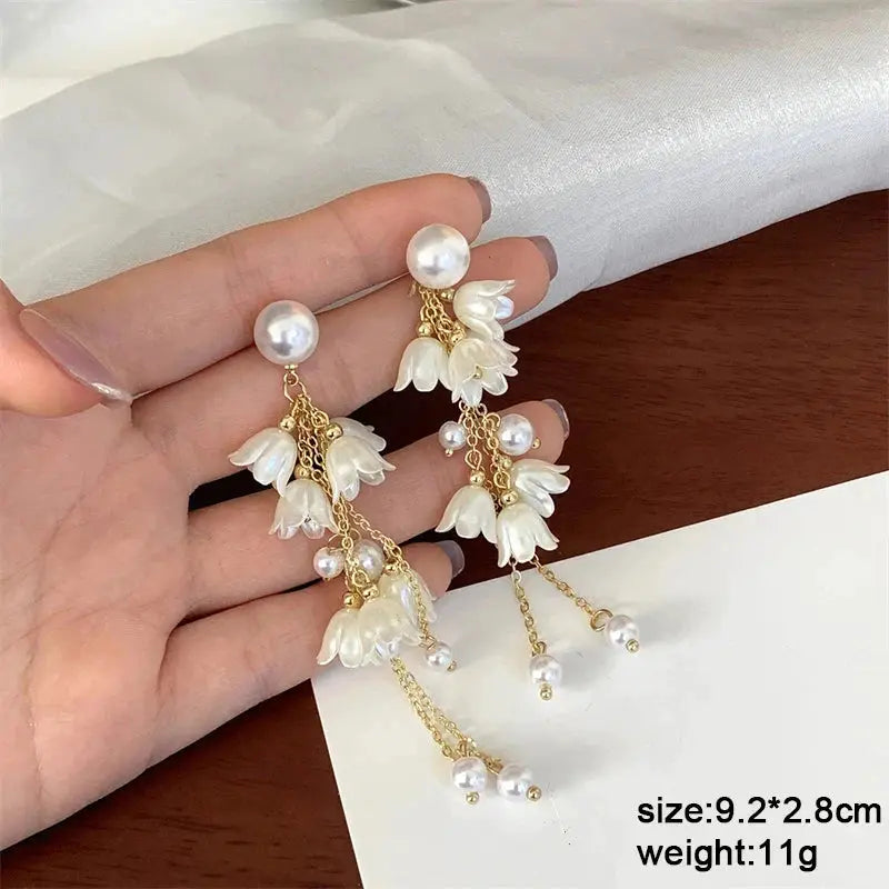 Pair of white flower acrylic enamel dangle earrings with pearl accents and gold-tone chains