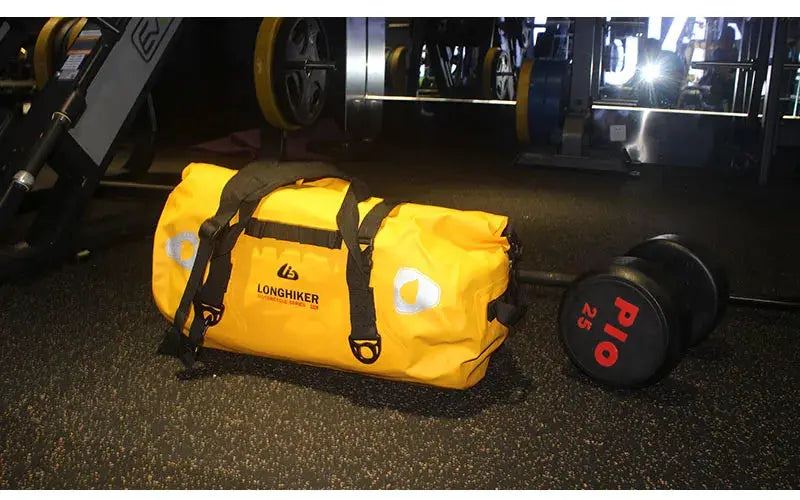 Yellow waterproof duffle bag with black straps and LONGHIKER logo in a gym beside weights