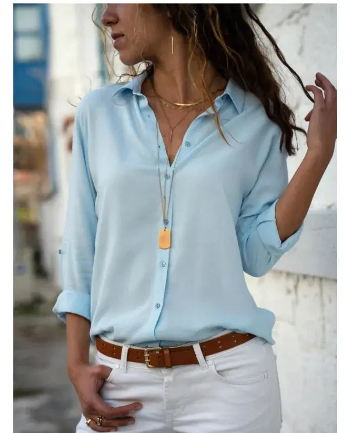 Autumn shirt women's polo-collar blouse in light blue with button-down front; brown belt and white pants.