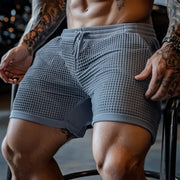Men's oversized stretch waffle shorts, gray waffle-knit fabric with elastic waist and breathable quick-dry comfort.