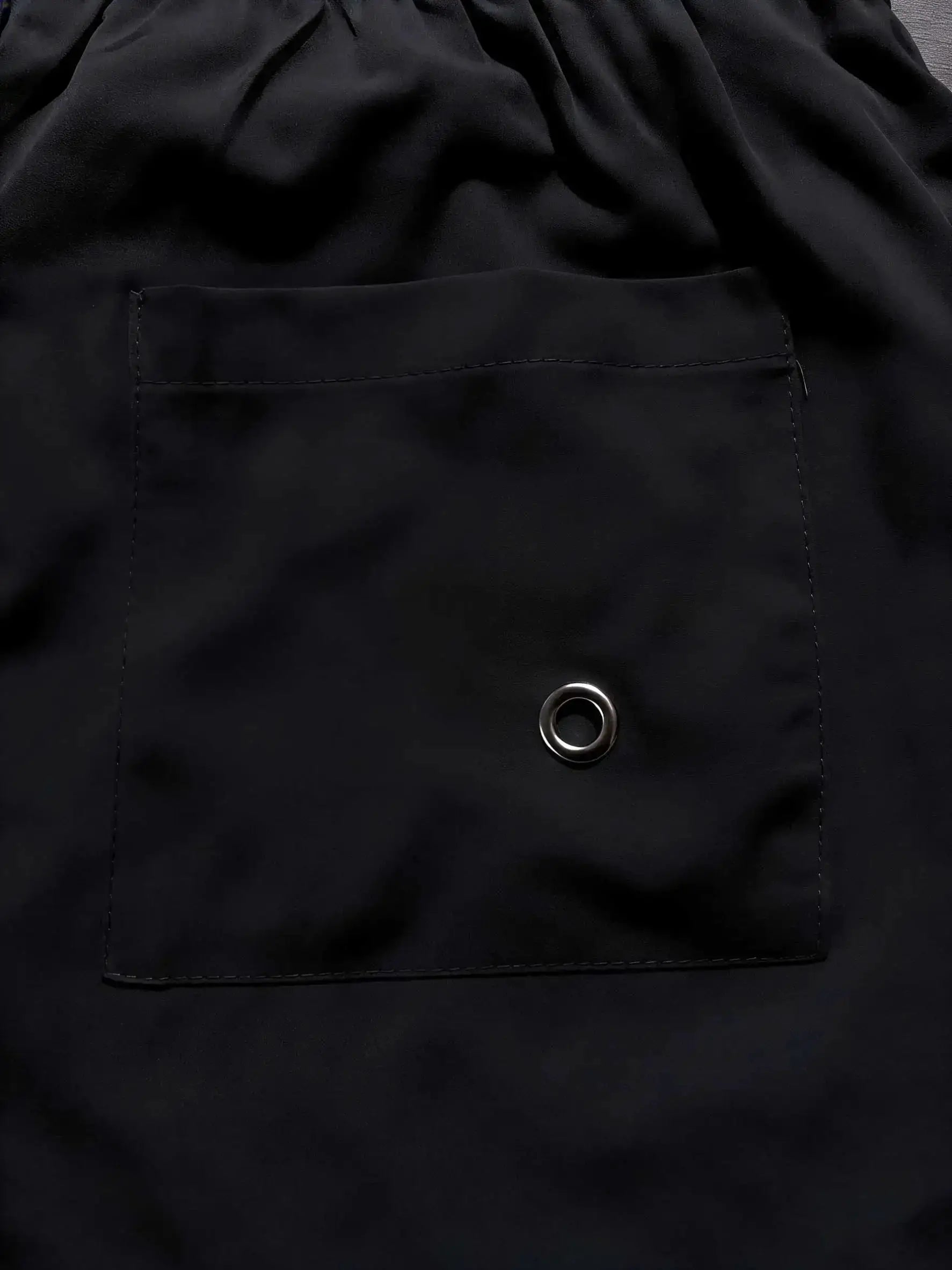 Simples Market men's black swim trunks with pocket and metal grommet.